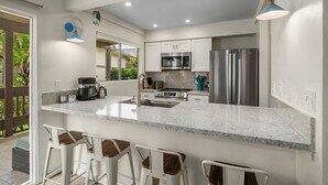A modern kitchen with a large island, stainless steel appliances, and bar stools.