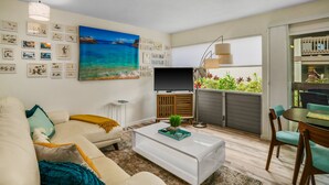 A living room with a sofa, coffee table, TV, and artwork on the wall.