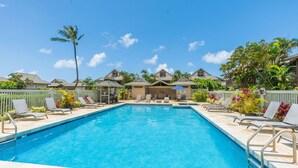 A rectangular swimming pool with clear blue water, surrounded by lounge chairs and umbrellas.