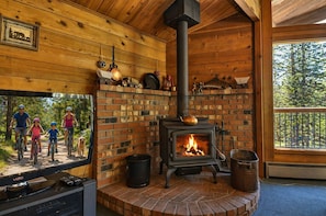 A rustic cabin with a brick fireplace, wooden walls, and a television. - 4 Flat Top-Sunriver, Oregon: Hot Tub, BBQ, WiFi, SHARC Aquatics, Tubing Hill, Mt. Bachelor, Golf, Deschutes River, Tennis, Bike Paths (Sunriver)