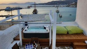 En balkon med jacuzzi, træterrasse og et bord med flasker og glas.