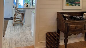 Un couloir doté d’un plancher en bois, d’un lustre, d’un banc en bois et d’un tableau encadré accroché au mur.