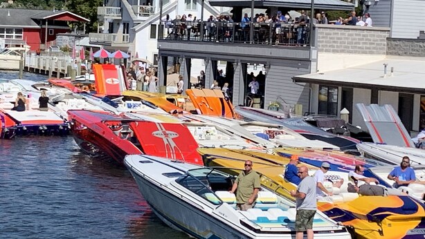 Een jachthaven met verschillende boten afgemeerd, een overdekt zitgedeelte en een gebouw met een balkon met uitzicht op het water.