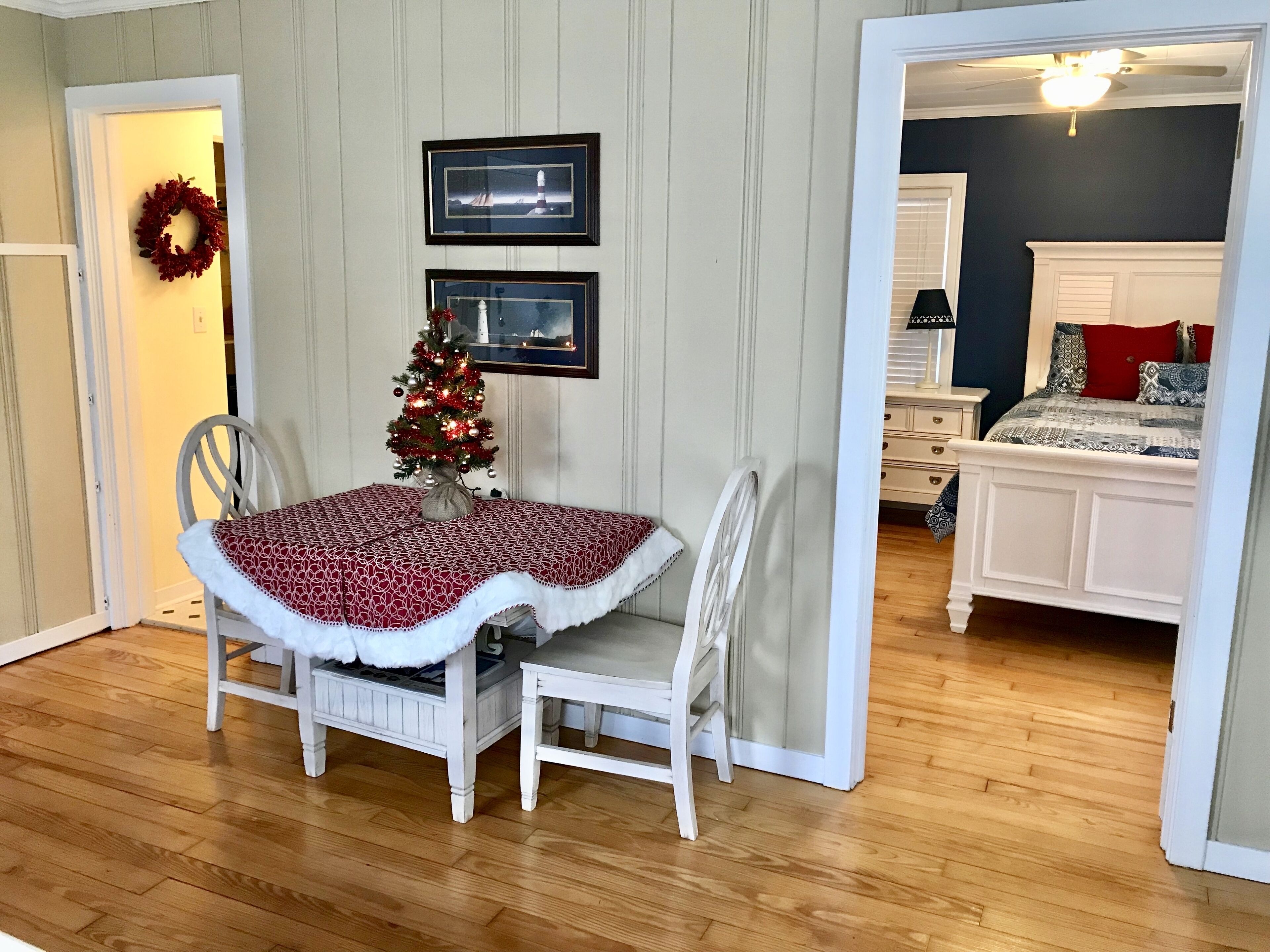 Un comedor con un árbol de Navidad, cuadros en la pared y vistas a un dormitorio con cama y cómoda.