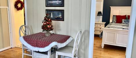 Un comedor con un árbol de Navidad, cuadros en la pared y vistas a un dormitorio con cama y cómoda.