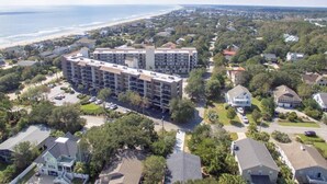 A multi-story hotel with a central courtyard, surrounded by residential houses and a beach in the background. - Gorgeous, Minutes to Beach, Updated Retreat 414 (Pawleys Island)