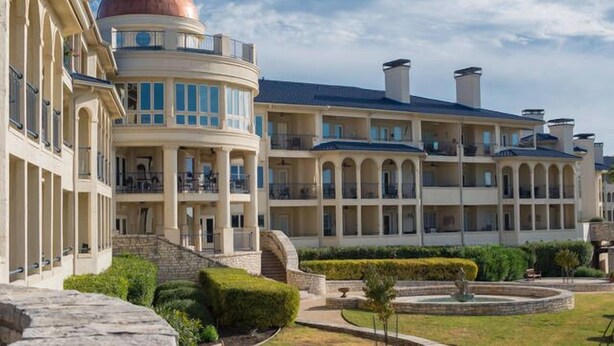 A large, multi-story hotel with a prominent dome structure, multiple balconies, and a landscaped courtyard. - Charming and spacious Villa with a big wrap around Balcony (Lago Vista)