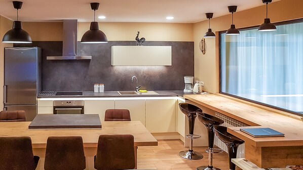 A modern kitchen with a central island, bar stools, and a large window.