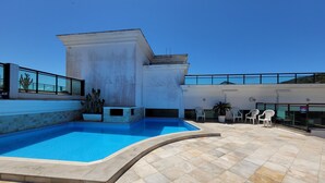 Une piscine à bord incurvé, entourée d’une terrasse carrelée.