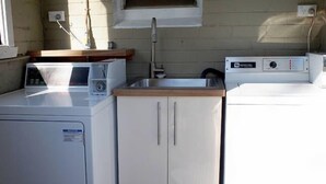A compact laundry area with a washing machine, a dryer, and a small cabinet with a sink. - Toogooloowa on Davey 5 (Hobart)