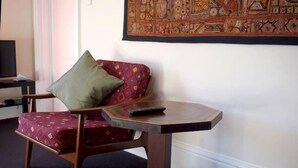 A wooden chair with a patterned cushion and a remote control on a small wooden table. - Toogooloowa on Davey 5 (Hobart)