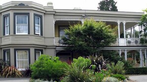 A Victorian-style house with a bay window, a balcony, and a garden with various plants. - Toogooloowa on Davey 5 (Hobart)