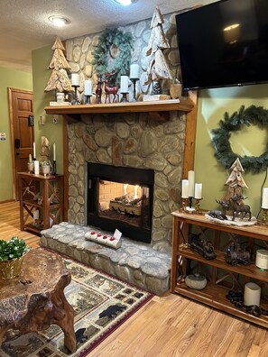 Cozy living room with a fireplace, flat-screen TV, and rustic decor.