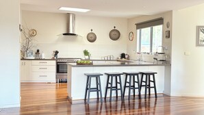 A modern kitchen with a central island, bar stools, and a large window.