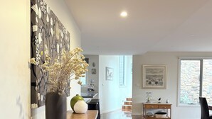 A spacious living area with a wooden floor, a dining table, and a kitchen in the background.