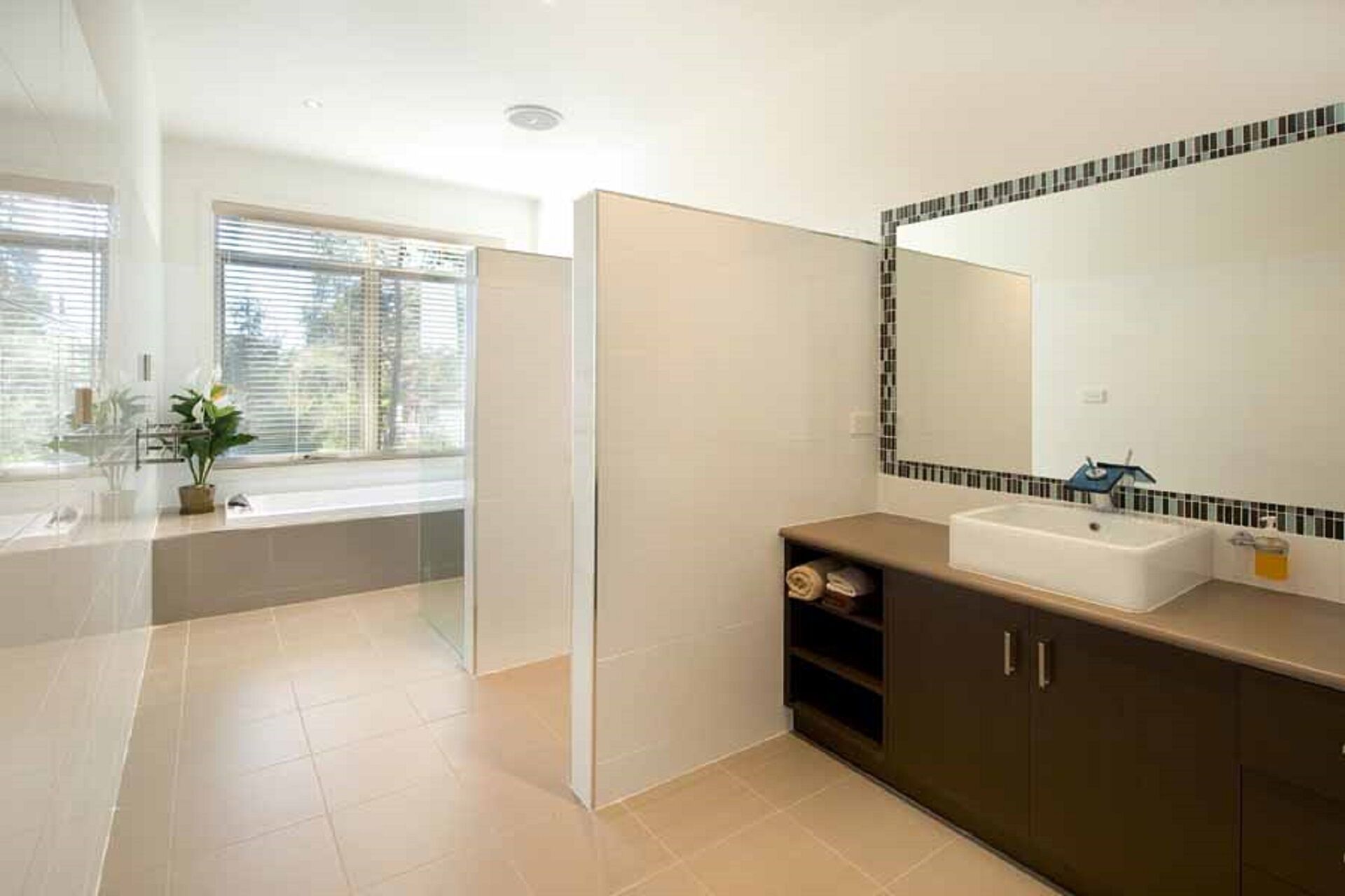 A modern bathroom with a bathtub, a large mirror, and a sink.