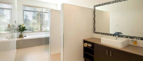 A modern bathroom with a bathtub, a large mirror, and a sink.