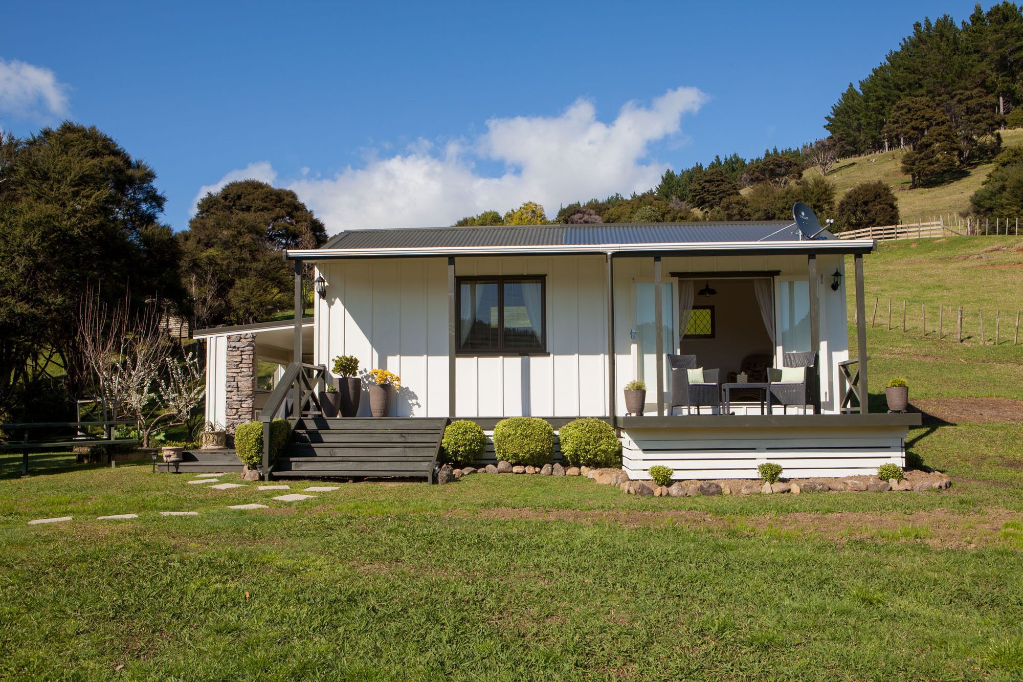 Une maison de plain-pied avec un porche couvert, des marches en pierre et un petit jardin.
