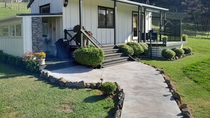 Une maison de plain-pied avec un mur d’accent en pierre, un porche à l’avant et une petite terrasse.