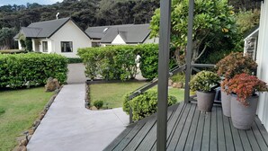 Une terrasse en bois avec un chemin en béton menant à une maison.