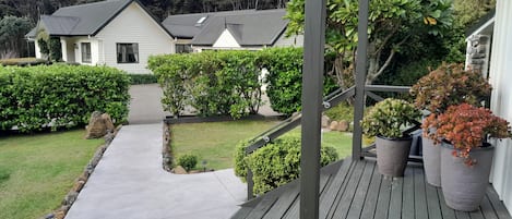 A wooden deck with a concrete pathway leading to a house.