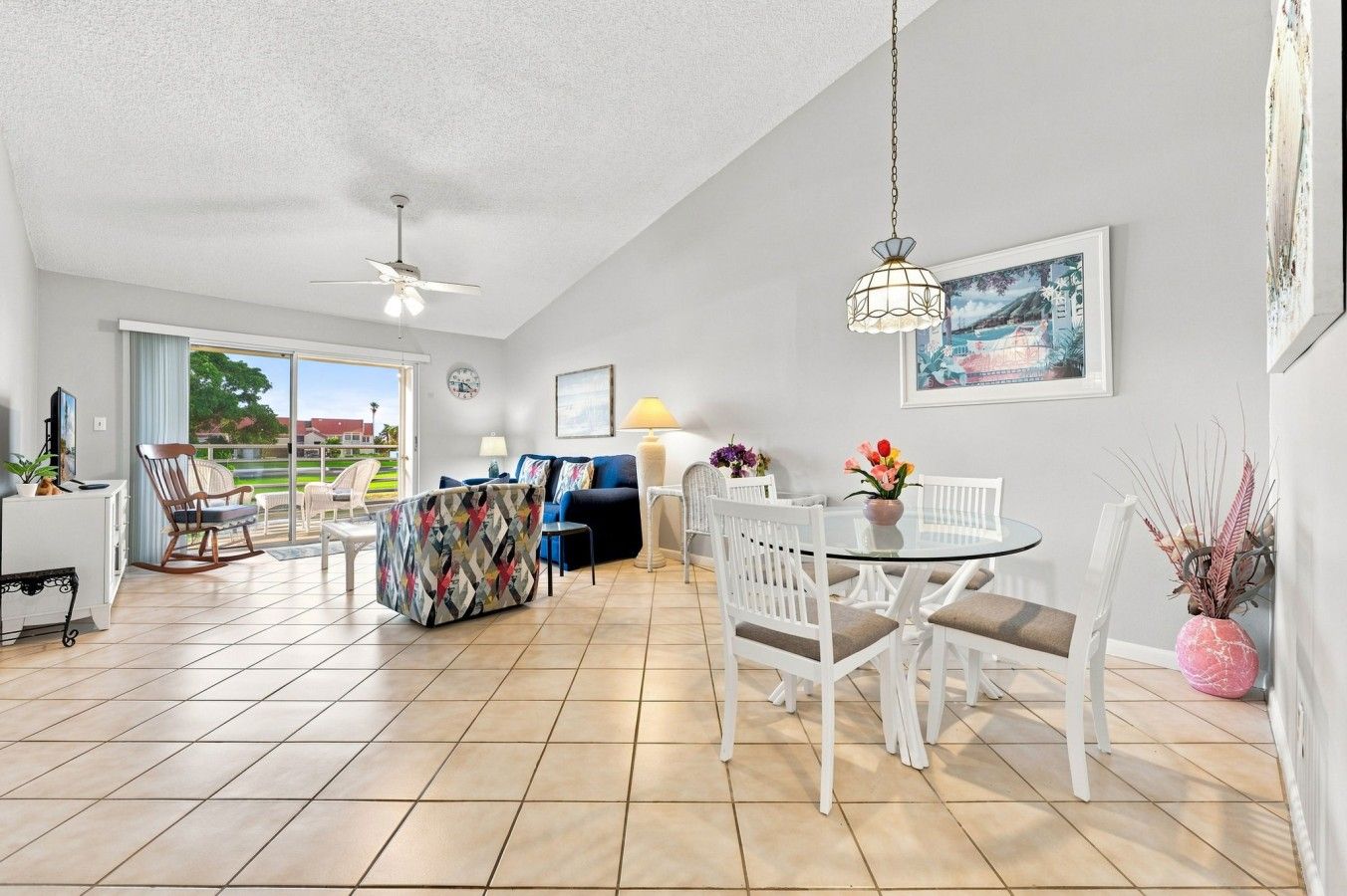 A spacious living area with a dining table, chairs, a sofa, and a ceiling fan.