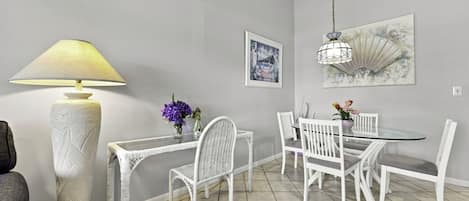 A dining area with a round table, white chairs, a tall floor lamp, and a hanging light fixture.