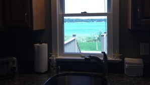Una cocina con vista a una masa de agua, un lavamanos empotrado y armarios de madera.