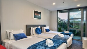 A hotel room with two beds, a large window with a view of mountains, and a staircase leading to an outdoor area.