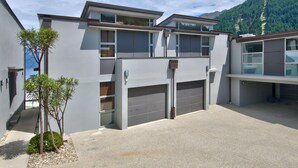 A modern two-story building with a garage and a small garden area.