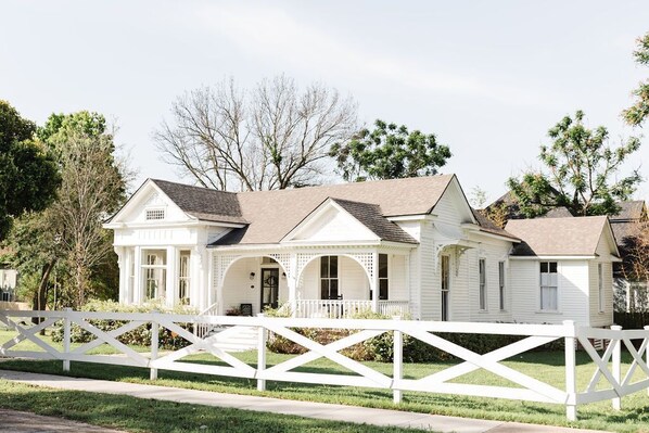 A two-story white house with a porch and a white picket fence. - Historical Morrow House Season 5 Fixer Upper, Featured In Cottage Style Magazine (Waco)