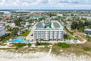 A large hotel with multiple floors, a central courtyard with a swimming pool, and a view of the surrounding cityscape. - Sunset Vistas 610N: Top Floor Gulf Front Beauty (Treasure Island)