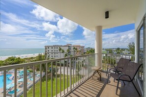 Un balcon avec vue sur la plage, la piscine et les bâtiments environnants.