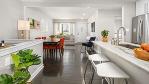 Eine moderne Küche mit Marmorarbeitsplatte, Edelstahlgeräten und einem Essbereich mit einer Couch und Stühlen.