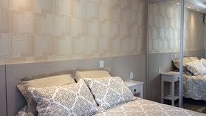 Une chambre à coucher moderne avec un grand lit, une table de chevet et un miroir.