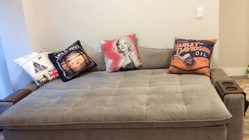 Ein graues Sofa mit drei dekorativen Kissen in verschiedenen Designs.