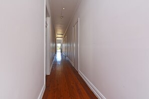 A long, narrow hallway with wooden flooring and white walls. - Parson's Vineyard Historic home amongst the vines (Rothbury)