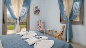 A bedroom with a bed, a chair, a small table, and a view of the outdoors.