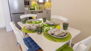 A dining area with a white table set for four, green placemats, and floral-patterned plates.