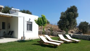 A white building with a patio area, outdoor seating, and a view of the landscape.