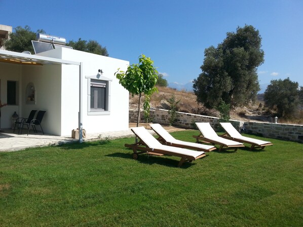 A white building with a patio area, outdoor seating, and a view of the landscape.