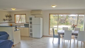 A kitchen with a refrigerator, microwave, and a dining area with chairs and a table.