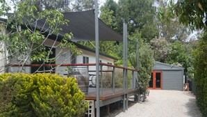 A house with a deck, a barbecue grill, and a shed.