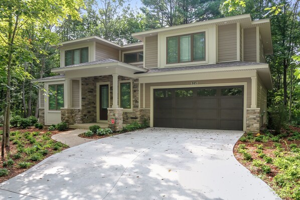 A two-story house with a stone facade, a garage, and a landscaped driveway. - Modern luxury high end retreat close to downtown Saugatuck.  (Saugatuck)