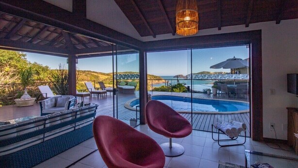Un intérieur moderne avec une piscine, des chaises rouges et une vue sur la mer.