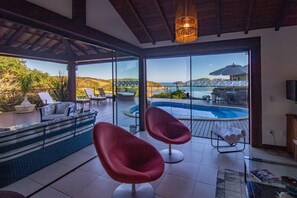 Un intérieur moderne avec une piscine, des chaises rouges et une vue sur la mer.