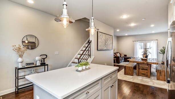 A modern kitchen with a central island, stainless steel appliances, and a dining area with a wooden table and benches.