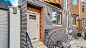 A modern townhouse with a brick facade, a white front door, and a small porch with steps.