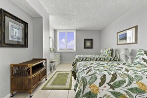 A bedroom with a bed, dresser, and a window. - Bay Front Serenity: 4th Floor 2BD/2BA at Isla Del (Isla Del Sol)