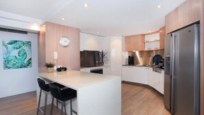 Uma cozinha moderna com ilha central, eletrodomésticos de aço inoxidável e armários de madeira.